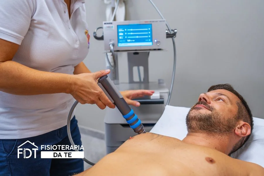 Fisioterapista applica il manipolo per onde d'urto sulla parte anteriore della spalla di un paziente per trattare una tendinite calcifica.