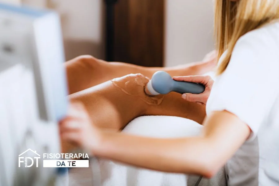 Fisioterapista esegue un massaggio circolare con la testina degli ultrasuoni sul ginocchio di un paziente per trattare dolore e gonfiore.